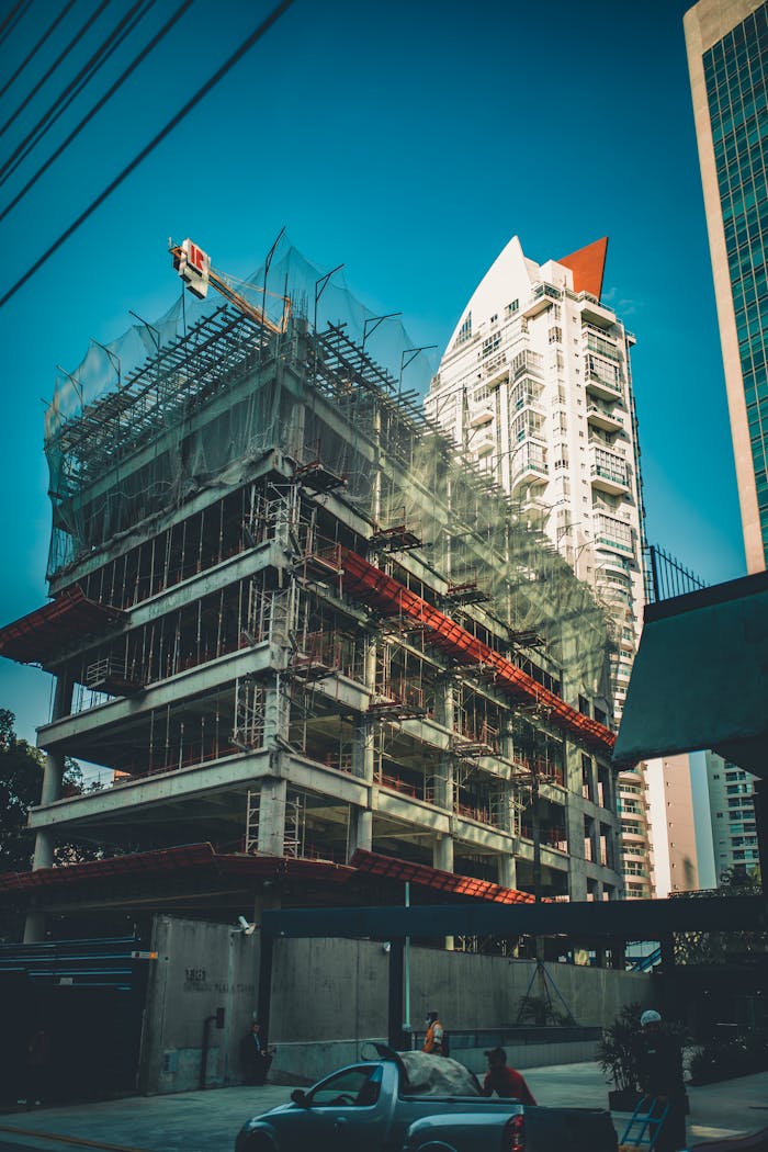 Services High-rise building under construction with scaffolding and crane in urban cityscape.